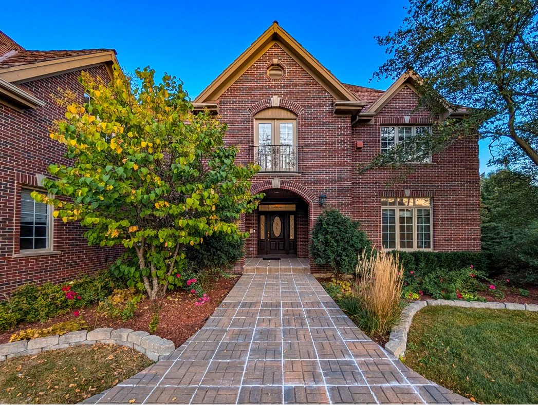 A brick home with an arched entry and a paver walkway